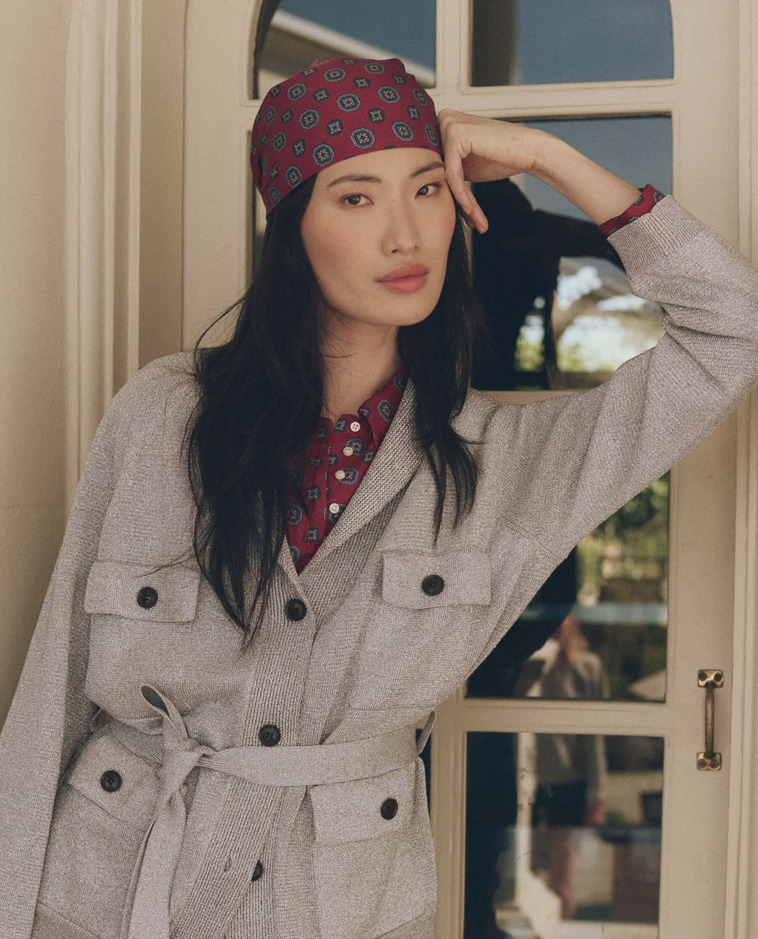 Gray Lurex Commander Riding Cardi belted over a maroon patterned shirt and matching headscarf.