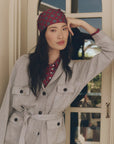 Gray Lurex Commander Riding Cardi belted over a maroon patterned shirt and matching headscarf.
