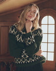 The Arctic Fairisle Pullover, a vintage forest green sweater with white geometric patterns, worn by a woman.