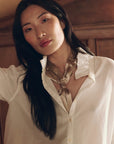 Shiny gold Pleated Neck Tie with metal ring, worn with a white button-down shirt by Bungalow Furniture & Accessories.