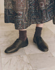 Dark metallic Lurex ankle socks paired with black leather lace-up flats and a patterned midi skirt.