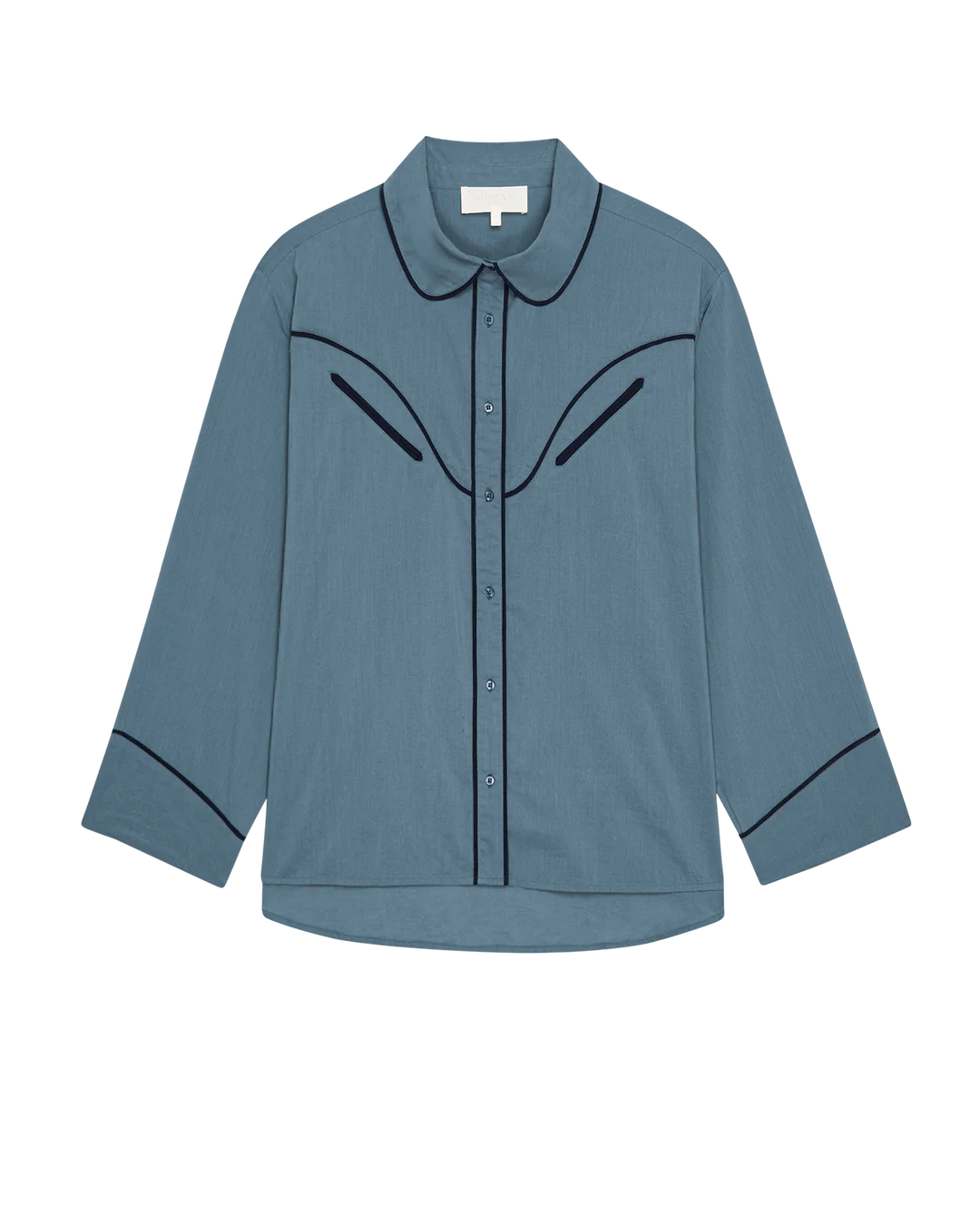 The Great Inc.’s The Pajama Shirt is a blue long-sleeve button-up with a rounded collar, black piping on the chest, collar, and cuffs, and features a relaxed fit with classic sleepwear styling.