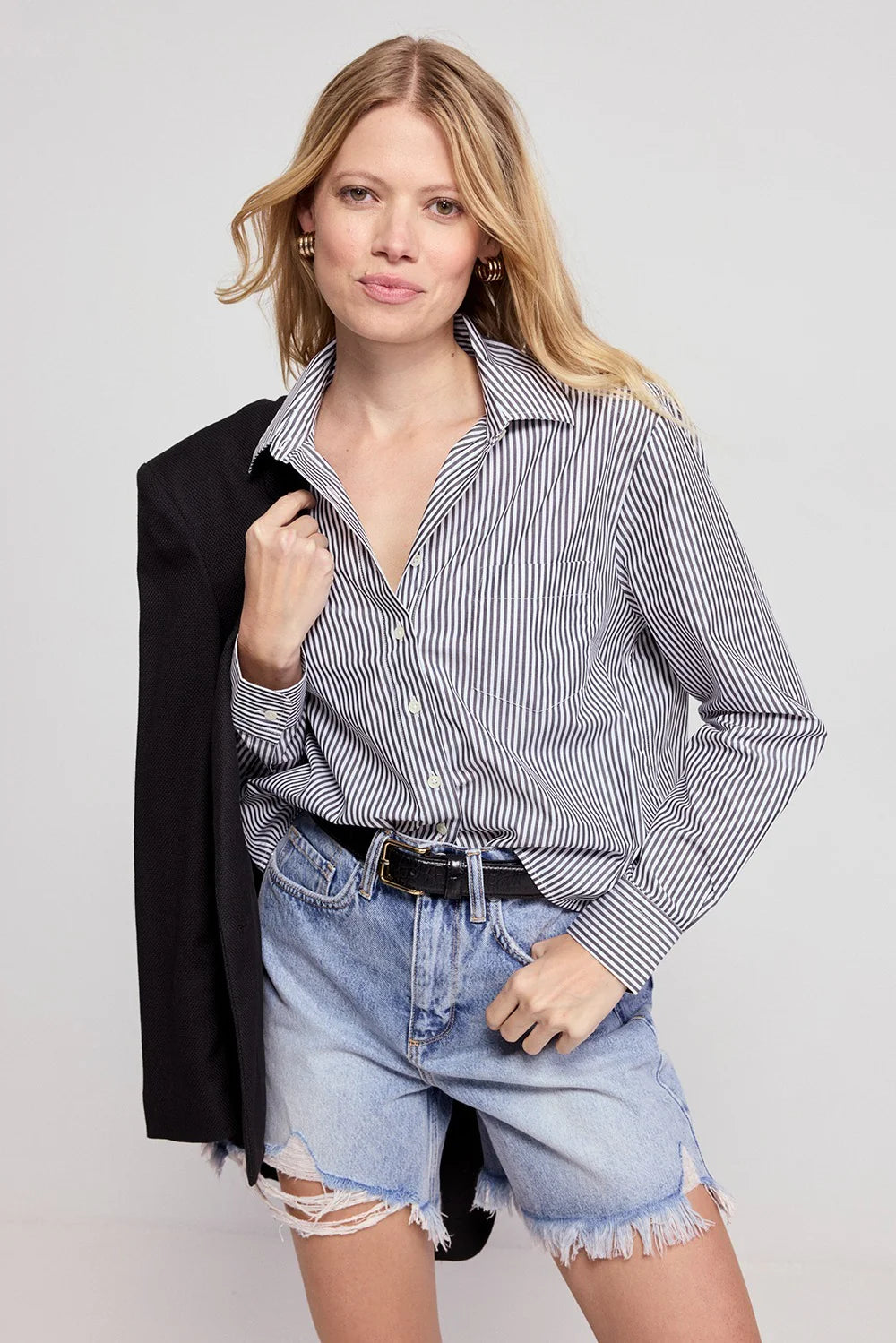 LS Boxy Crop in black and white stripe by THE SHIRT, styled with a jacket over the shoulder in a light, airy setting.