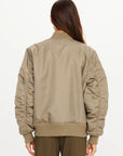 The Upside Tribute Bomber Jacket in olive, shown from the back, styled with brown pants.
