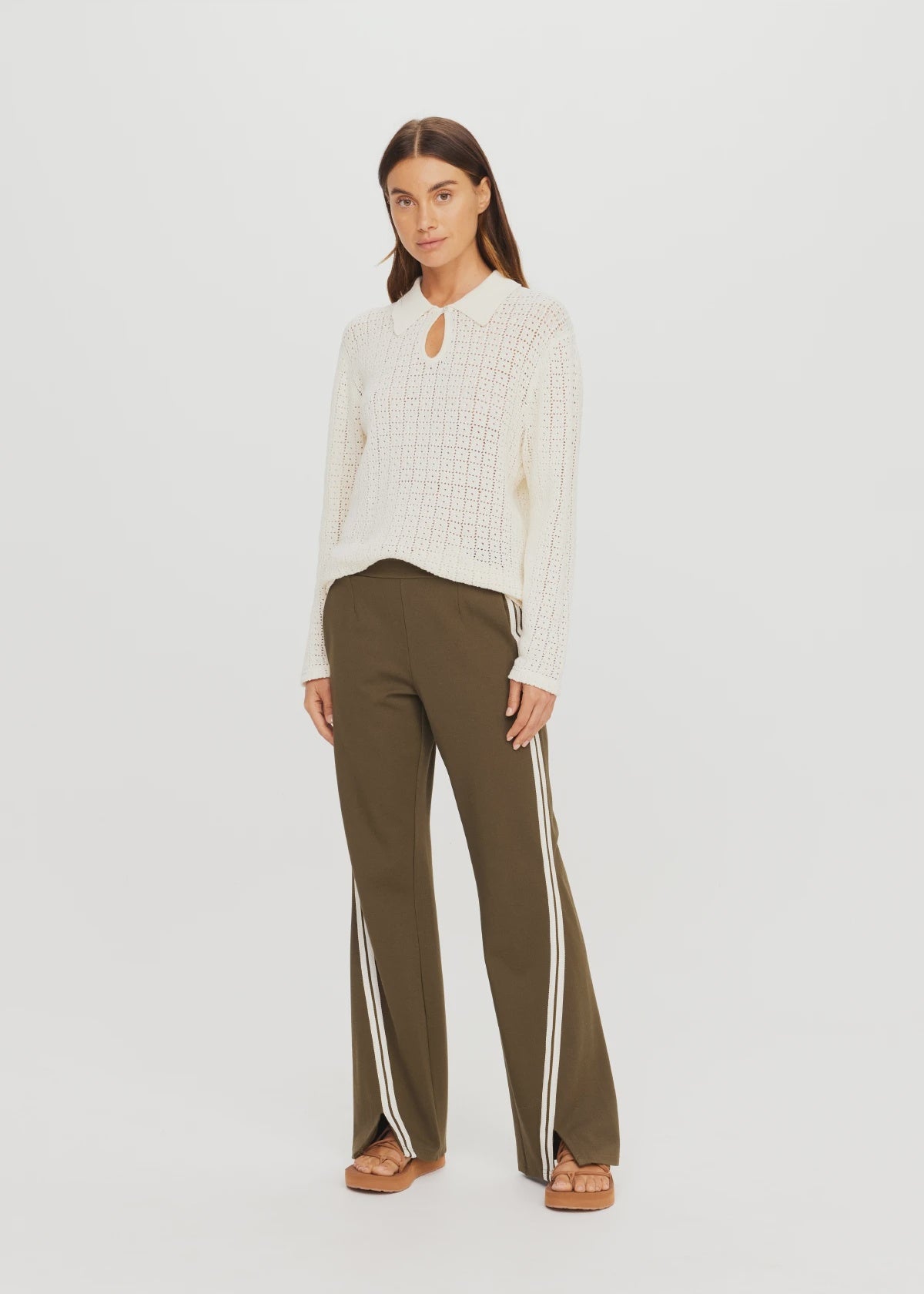 The Upside PETRA FLARE PANT with a white knit sweater, modern minimalist style against plain background.