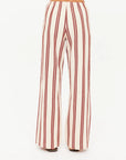 A person is shown from the back wearing The Upside's BAJA CHARLI DRAWSTRING PANT, featuring high-waisted, straight legs with vertical burnt red and white stripes, set against a plain white background.