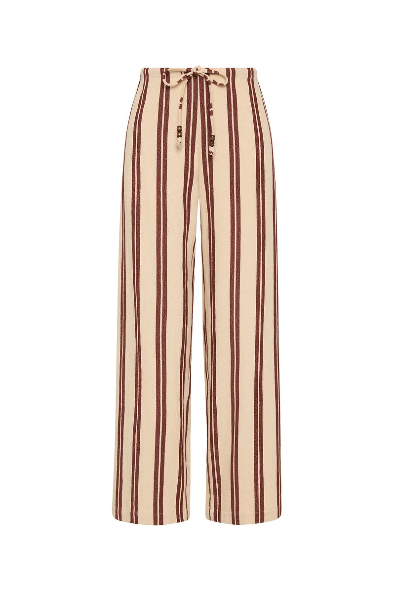 The Upside's BAJA CHARLI DRAWSTRING PANT features beige organic cotton, vertical burnt red stripes, a drawstring waist, and a relaxed wide-leg fit.