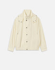 The Seersucker Track Jacket by FRAME is a cream long-sleeve seersucker jacket with snap buttons, front pockets, high collar, adjustable drawstrings, and an elasticated hem, shown on a white background.
