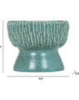 The Norlin Bowl by The Import Collection features a blue-green ceramic finish with textured vertical ridges on the top half and a smooth lower half. Measuring 7" tall and 5.5" wide, it's ideal for tabletop displays as pictured.