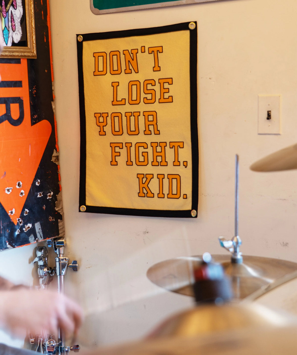Yellow motivational camp flag with bold black text by Faire, adds character to a modern wall; ideal for home decor.