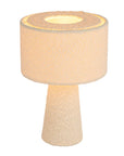 The Bouclé Ivory Fabric Table Lamp by Bloomingville features a textured off-white cylindrical shade and matching conical base in ivory, casting a warm, soft light—perfect for modern interiors.
