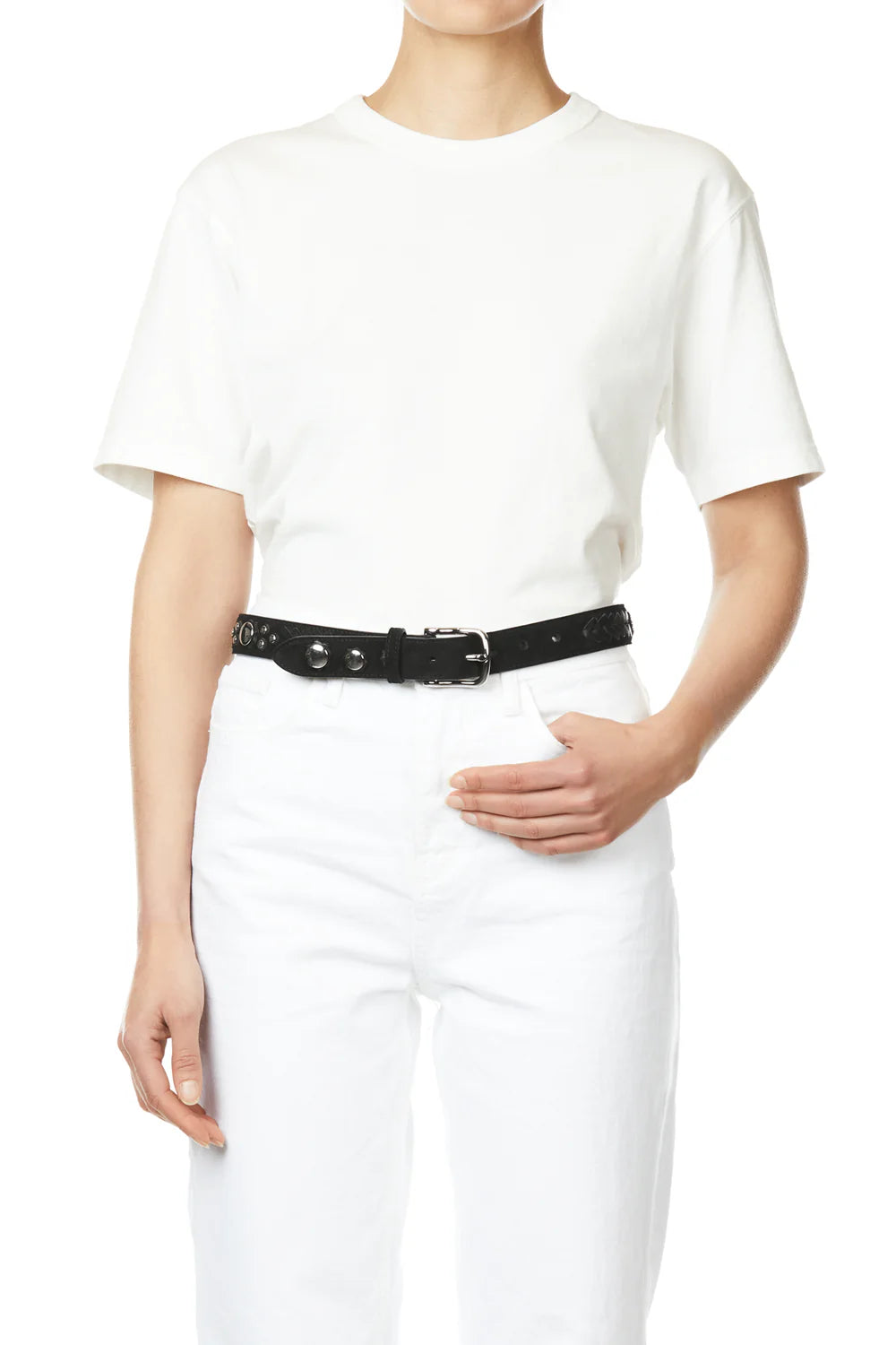 A person dresses in a plain white t-shirt and white pants, accessorized with Jerome Dreyfuss's Gaucho Ceinture belt, crafted from black cowskin calfskin and adorned with domed metal rivets. The minimalist background enhances the ensemble.