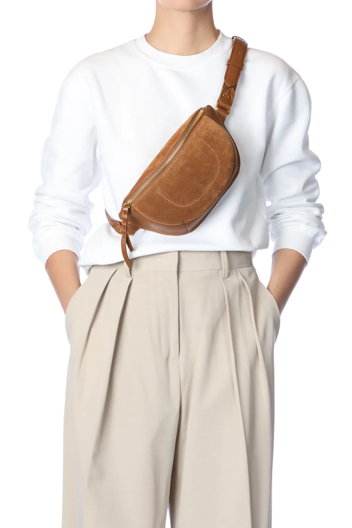 Jerome Dreyfuss Lino Banane bag styled with a white sweater and beige pleated pants, hands in pockets.