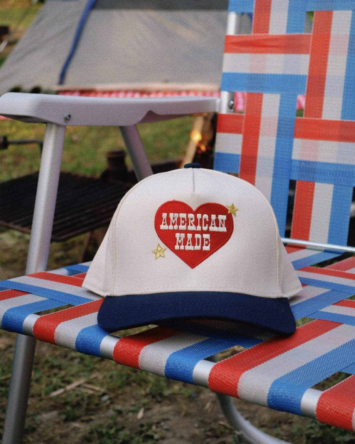 American Made embroidered trucker hat by The Faire on a red, white, and blue outdoor lawn chair.