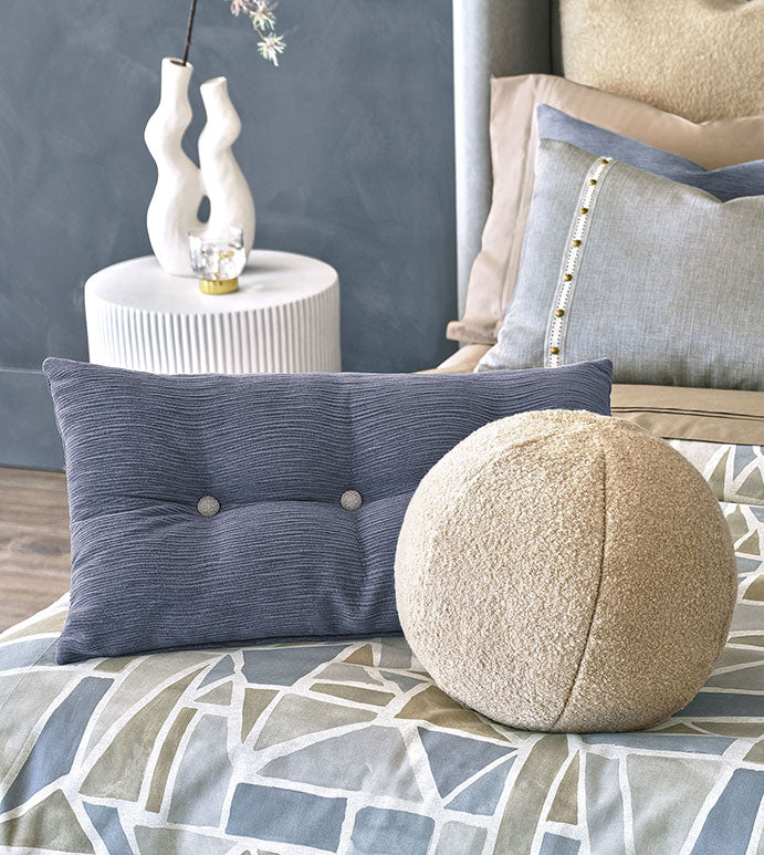 Navy tufted button pillow and cream Oliver Boucle spherical pillow on a geometric print duvet.