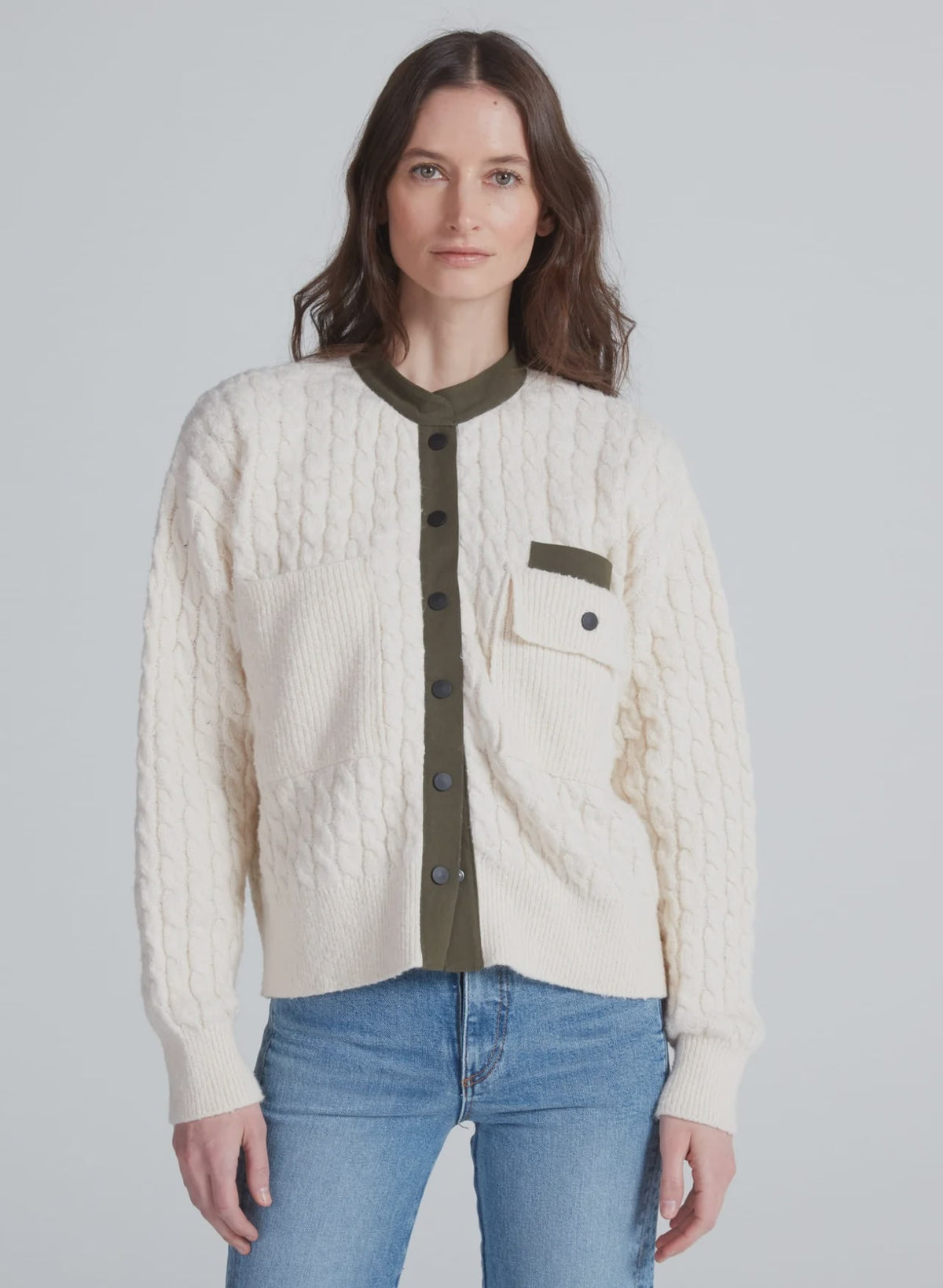 ASKK Greenwich Cardigan in cream cable knit, styled with a green shirt and blue jeans for a relaxed, cozy look.