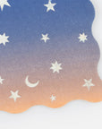 The Faire Making Magic Star Large Napkins feature wavy edges and an ombre gradient from blue to peach, adorned with white stars and a crescent moon—perfect for wizard-themed party decorations.