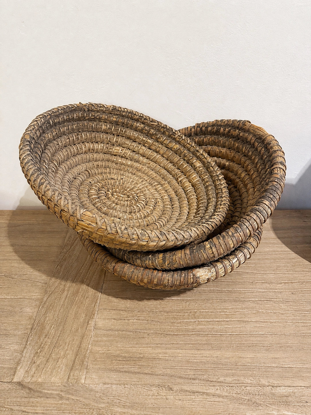 Stacked vintage French antique gathering baskets on a wooden table, Bungalow Furniture &amp; Accessories style.