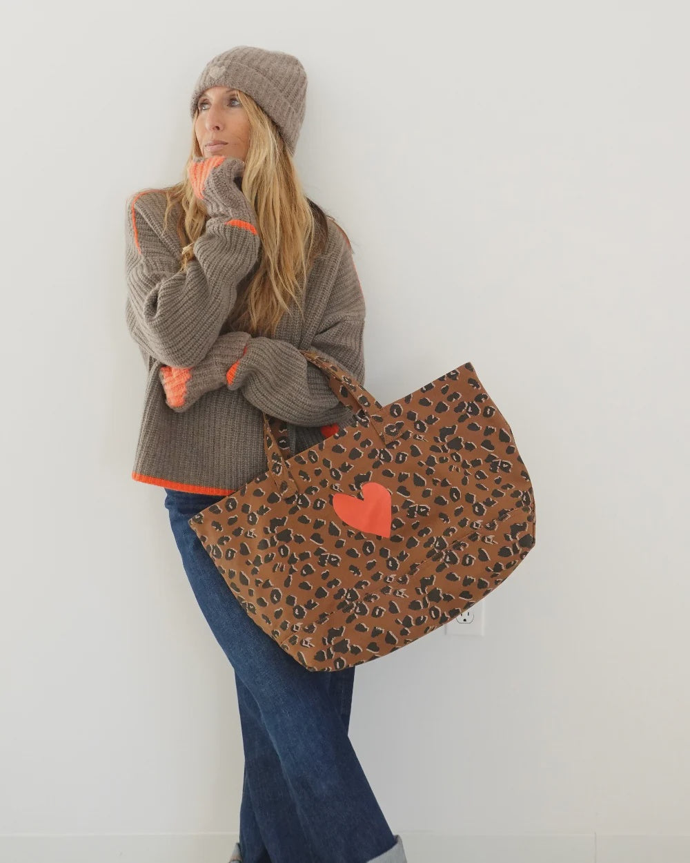 Kerri Rosenthal winter beanie and sweater with neon orange accents paired with a leopard print heart tote.