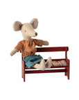 Maileg Mouse in striped shirt and blue skirt seated on red bench, Maileg, playful decor for kids’ rooms.