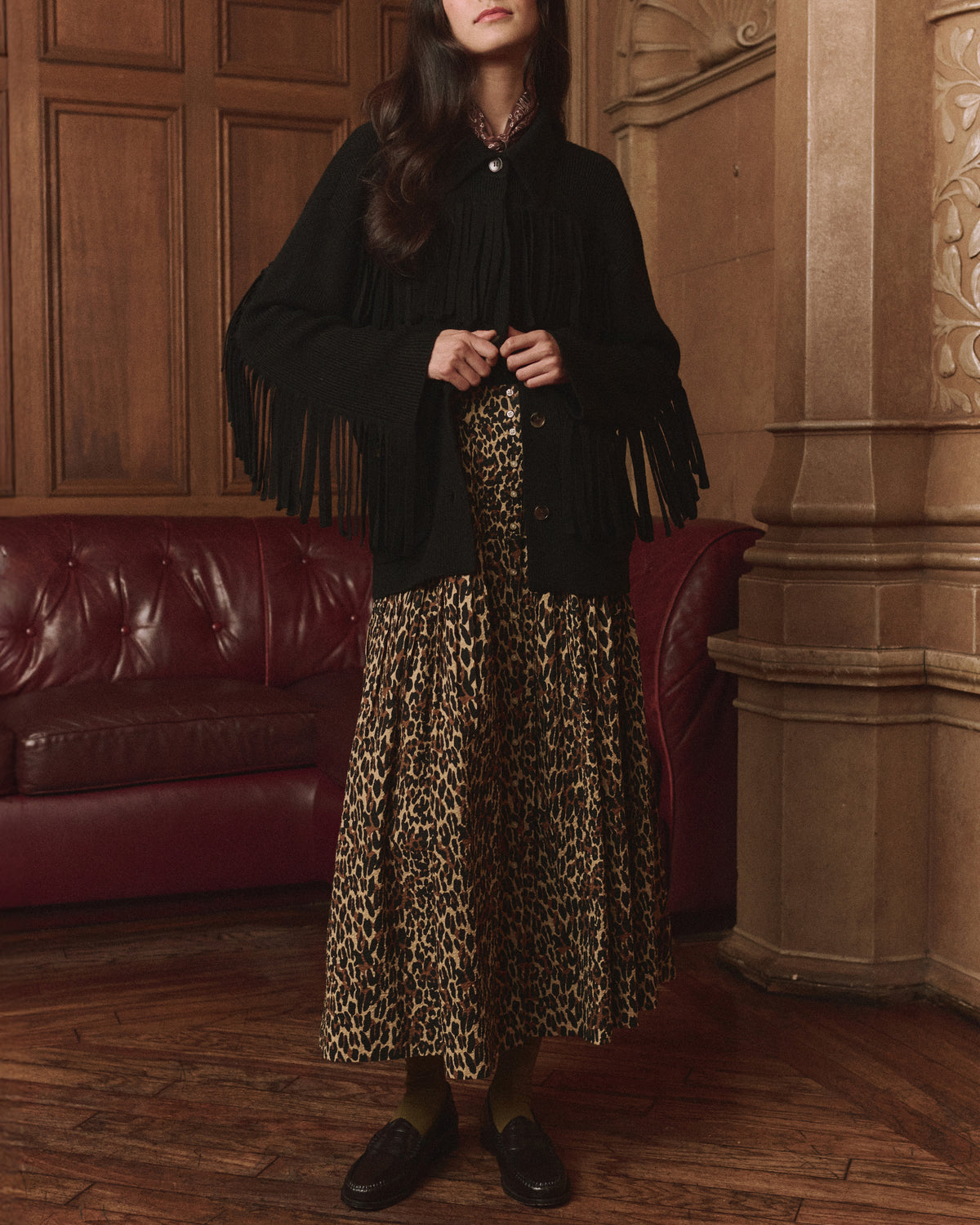 Western Fringe Sweater Jacket by The Great Inc. in a cozy living room with red couch and wood floors.