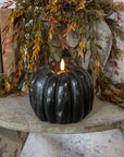 Black 3D flame pumpkin candle by Faire glows on rustic wood with fall garland, perfect for cozy autumn décor.
