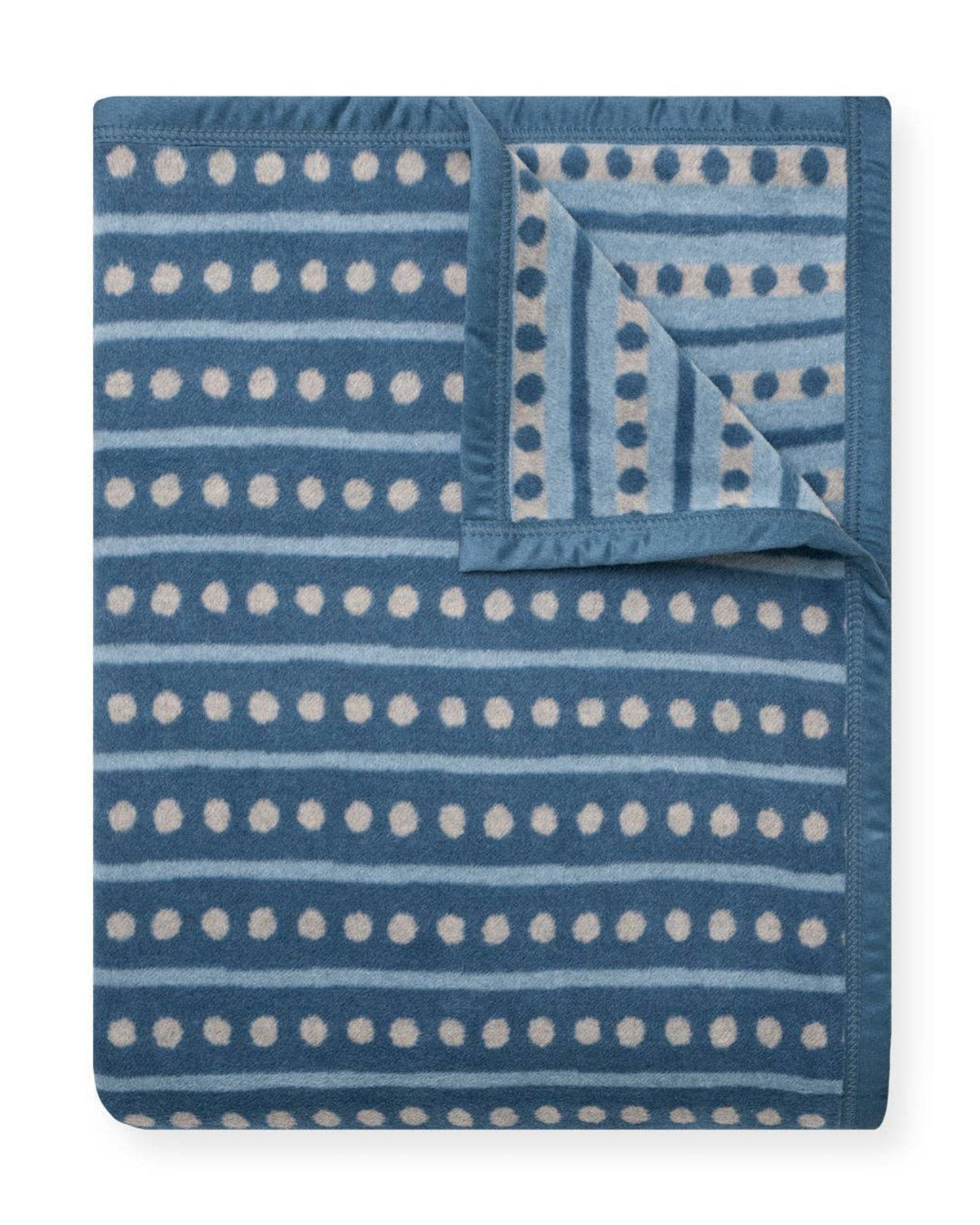Blue and white cornflower-patterned Faire Beach Pebble blanket with one corner turned to show the reverse side.
