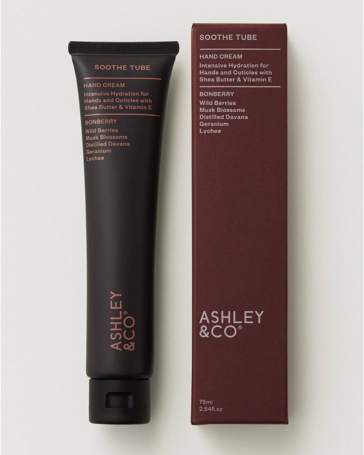 A black tube labeled "Ashley & Co Soothe Tube Hand Cream" stands beside its maroon box, featuring shea butter, Vitamin E, and a bonberry scent with wild berries, musk blossoms, geranium, and lychee.