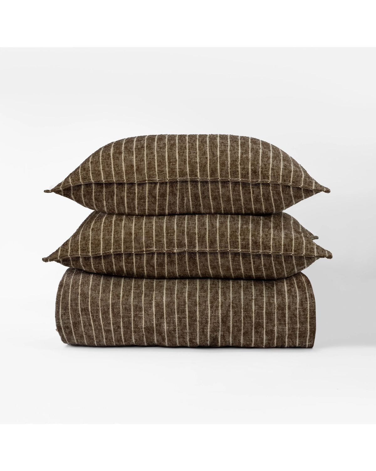 The Bruno Duvet Cover Queen by Amity Home, featuring brown fabric with thin vertical white stripes, is crafted from soft cotton and displayed folded with matching pillows against a plain white background for modern elegance.