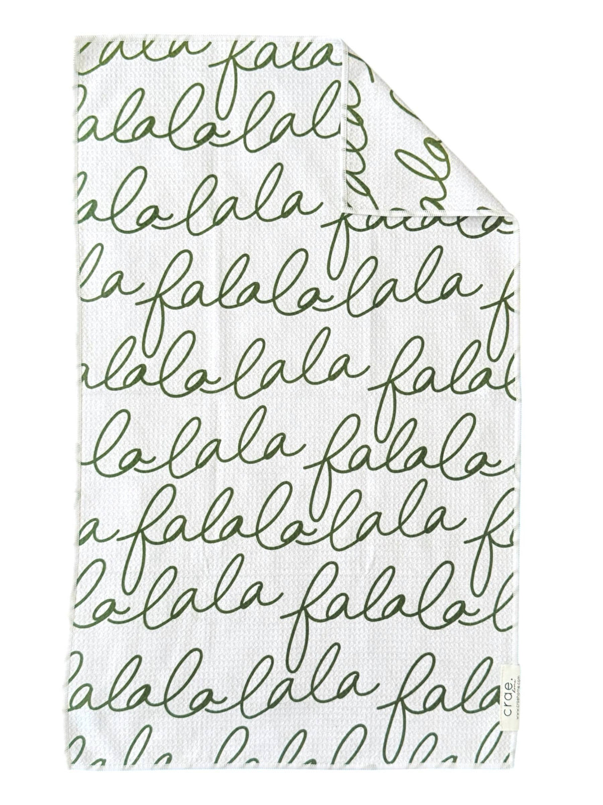 White waffle-weave hand towel with green cursive falalalala text from Bungalow Furniture &amp; Accessories.