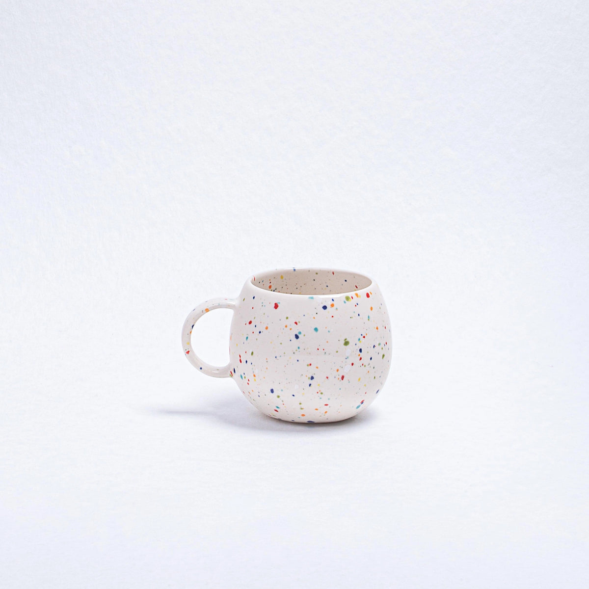 Round white stoneware Ball Mug with a colorful speckled pattern by Bungalow Furniture & Accessories.
