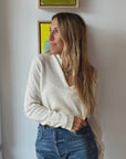 Femme Ruffle Henley Sweater in white by Kerri Rosenthal paired with blue denim jeans.
