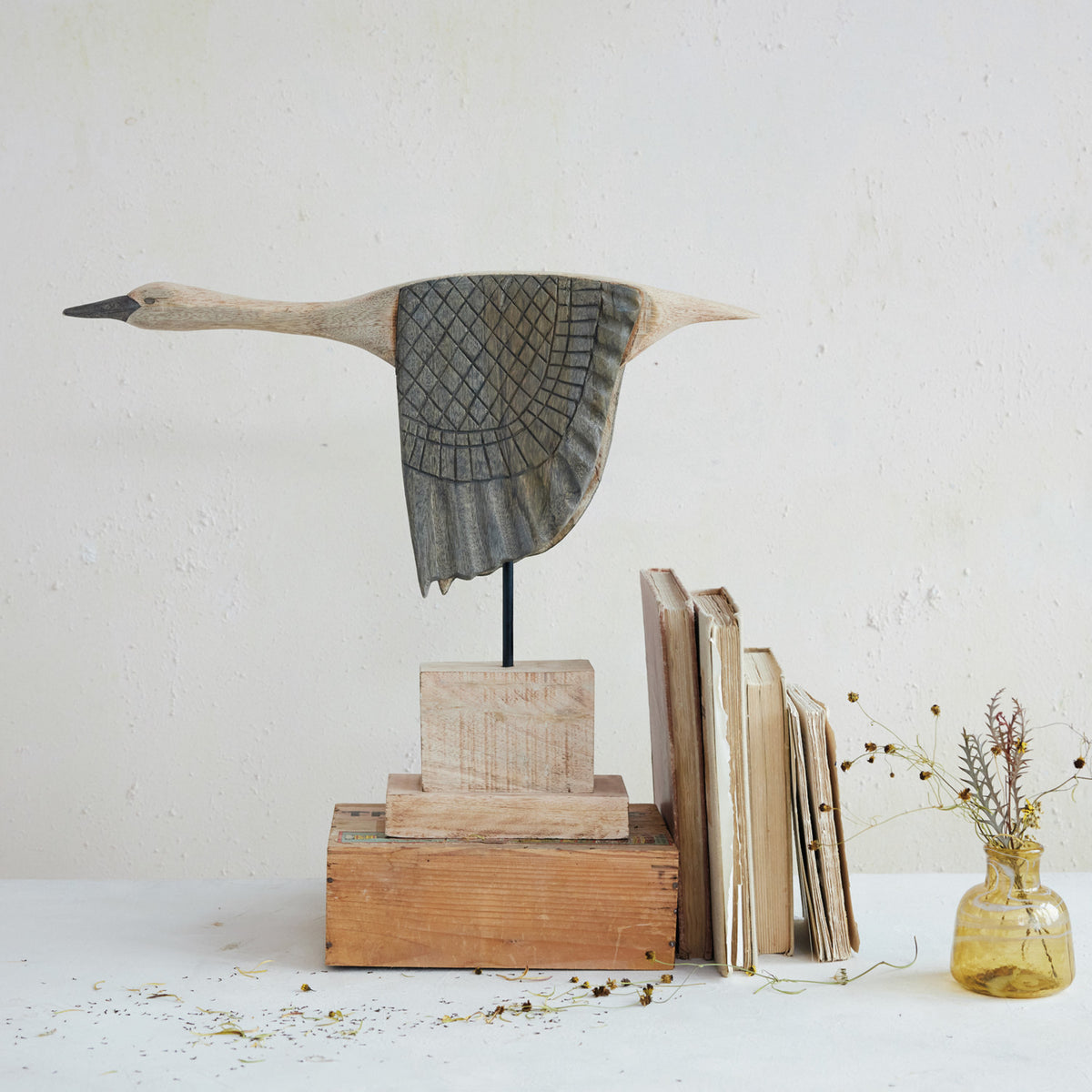 Goose sculpture by Creative Co-op displayed on a stand with vintage books and yellow dried flowers for a cozy accent.