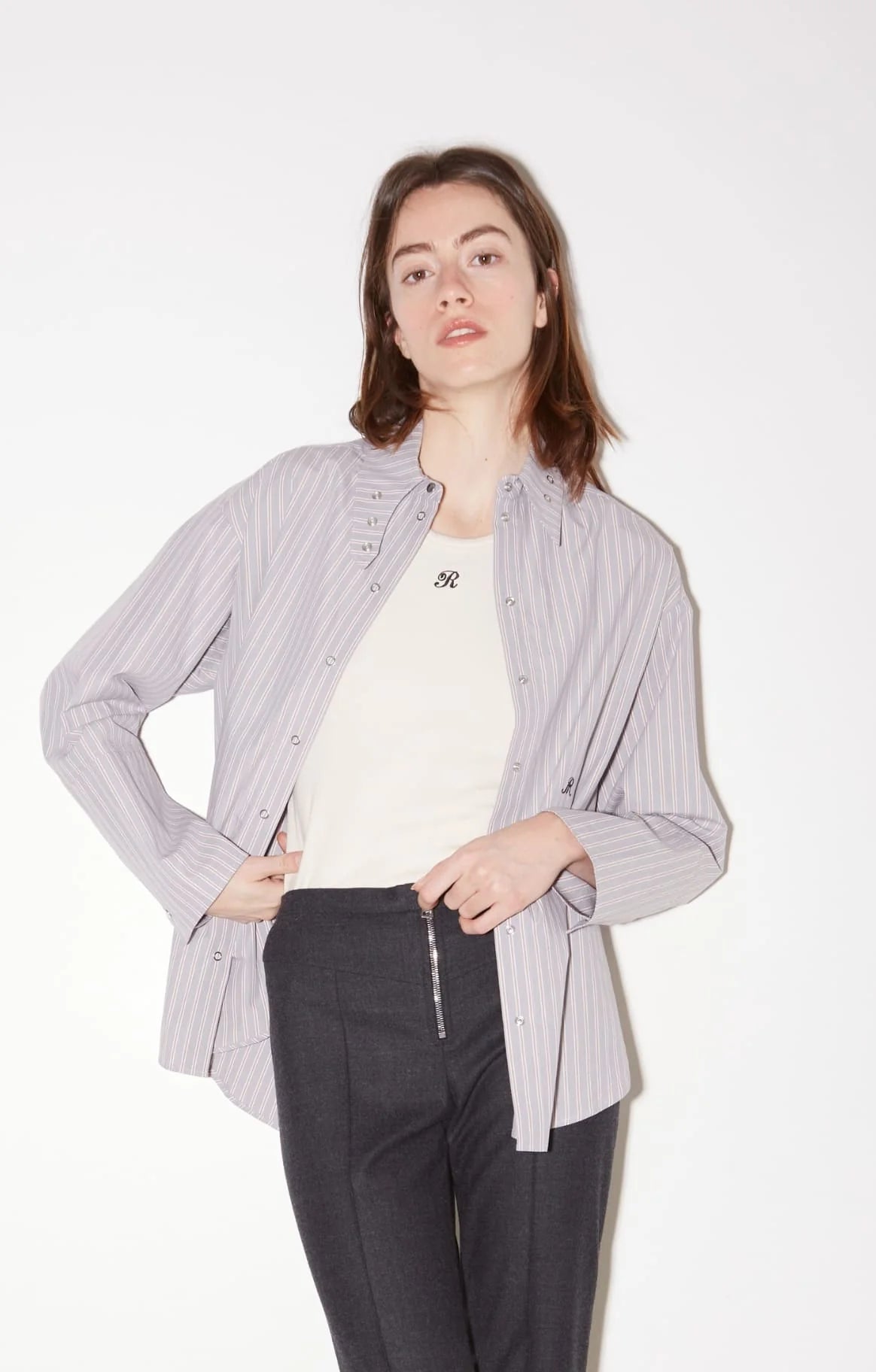 Lavender striped Roseanna Chemises shirt worn unbuttoned over a cream tank and dark grey trousers.