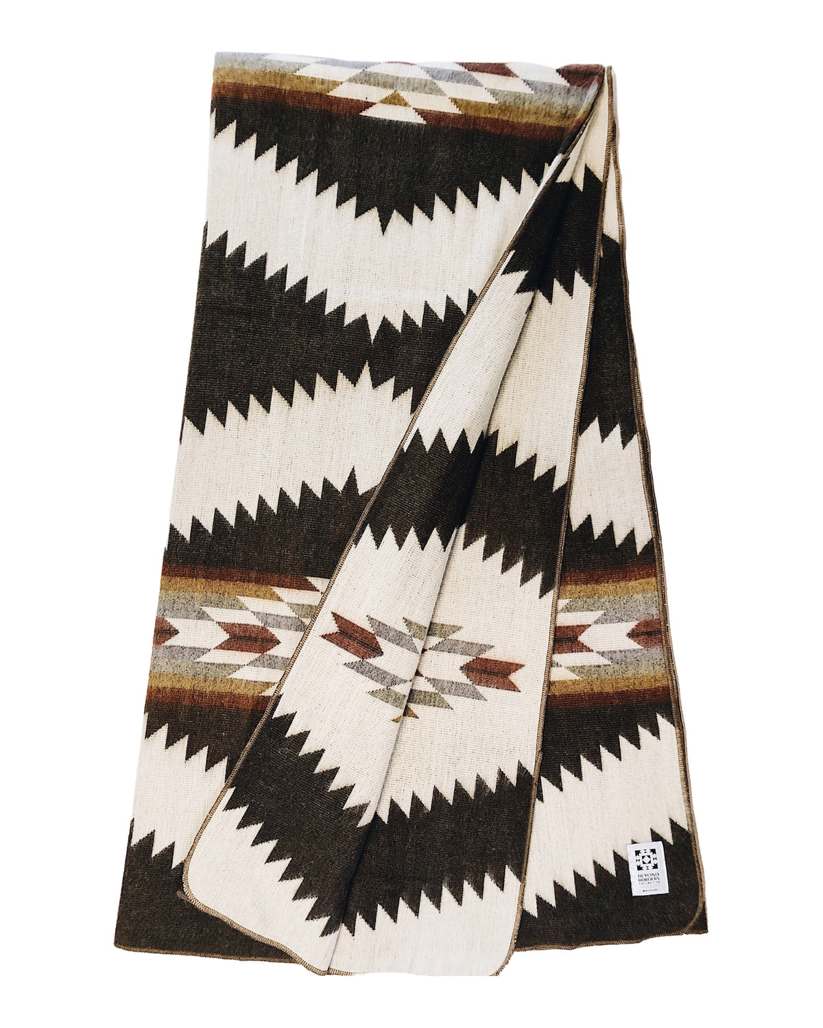 Folded chocolate Tsachila blanket by Bungalow Furniture &amp; Accessories featuring a brown and cream geometric zigzag pattern.