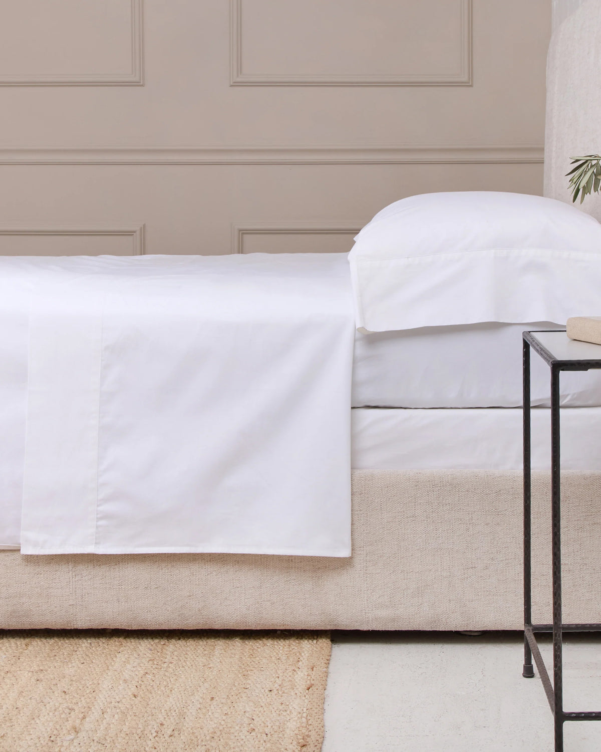 Queen bed dressed in POM POM cotton sateen sheet set with pillow, beside a black metal nightstand at Bungalow Furniture.