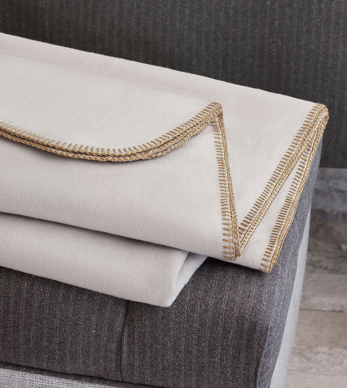 Pattinson Blanket Stitch Coverlet by Eastern Accents displayed on a gray striped upholstered bench.