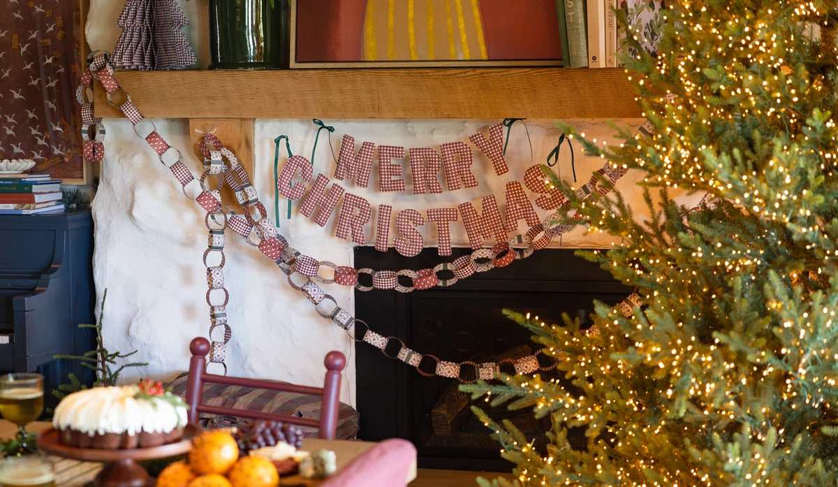 Merry Christmas fabric banner and paper chain garland in red and white gingham hanging on a mantel by Bungalow.