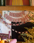 Merry Christmas fabric banner and paper chain garland in red and white gingham hanging on a mantel by Bungalow.