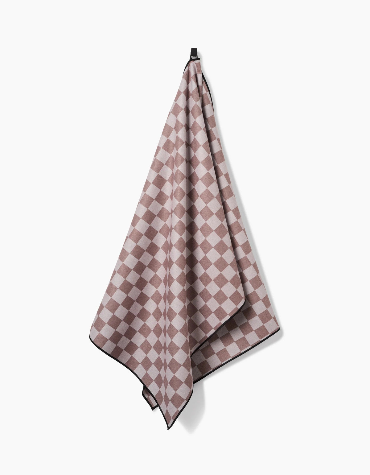 The Faire Chic Checker Yoga Towel in pink and beige checkered pattern with black trim hangs from a hook against a plain white background.
