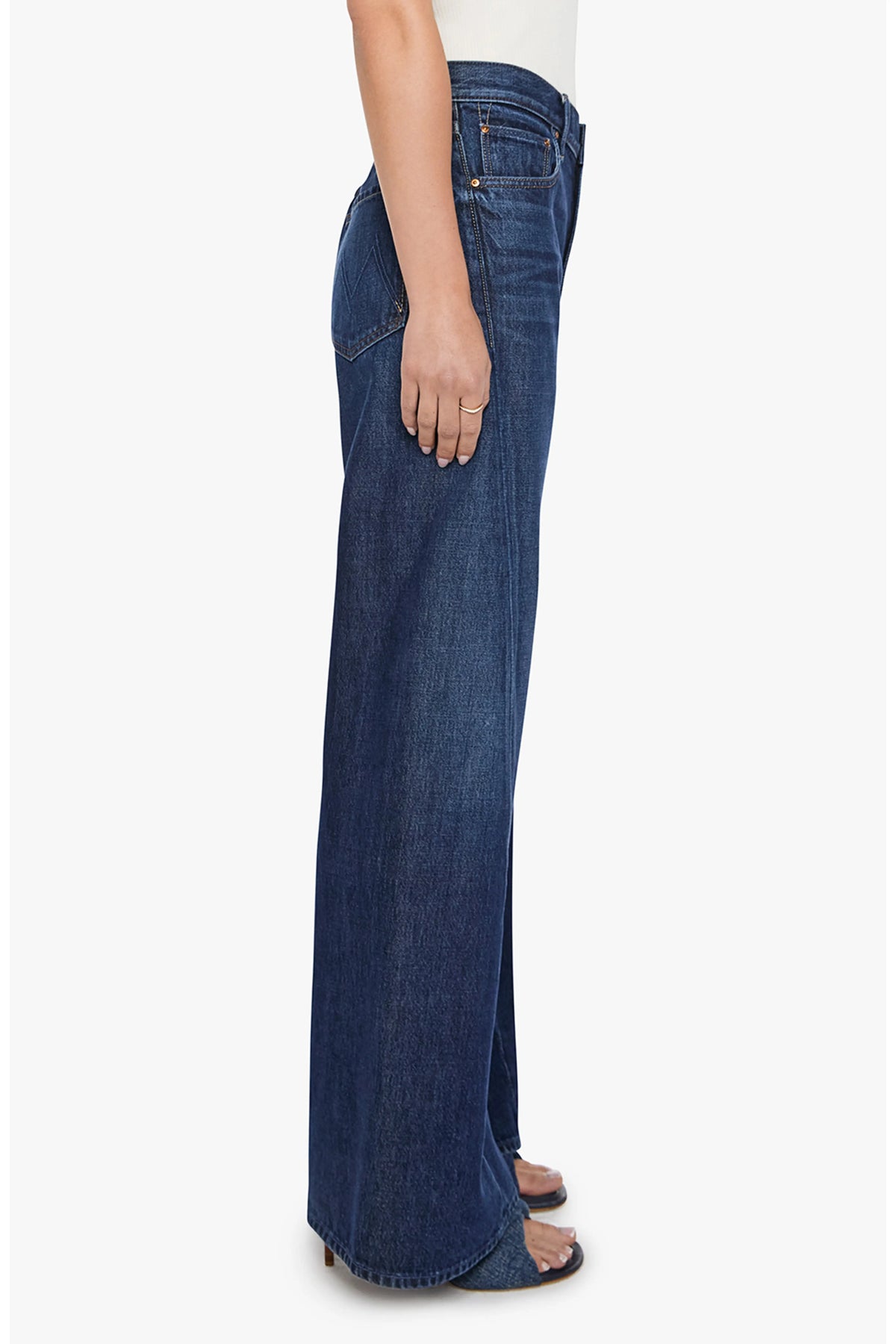 Mother Lil Lemon Twist Sneak high-waisted wide-leg jeans with twisted seams and navy blue heeled sandals, side view.