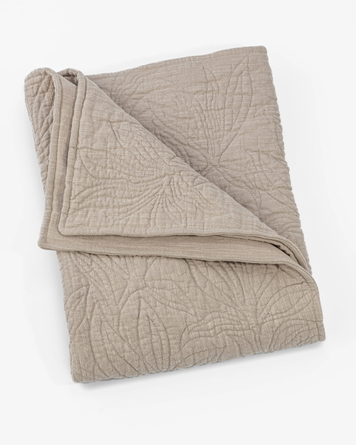 The Amity Home Davina Quilt Queen, in beige, showcases traditional elegance with a subtle stitched leaf pattern and floral quilting, neatly folded against a white background.
