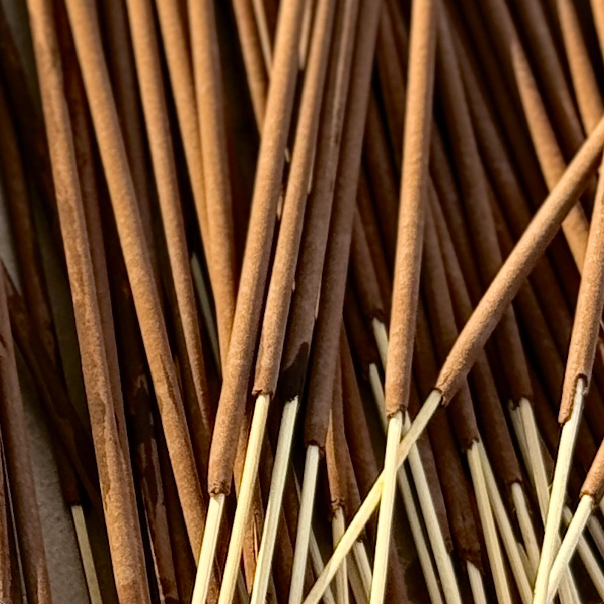 A close-up of several brown Lagoon Incense Sticks | Lush & Seductive by Faire, featuring wooden stems arranged in a scattered pattern for a luxurious fragrance and clean-burning incense experience.