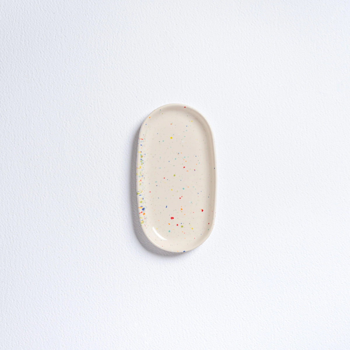 Small oval mini tray by Bungalow Furniture & Accessories in off-white stoneware with colorful confetti speckles.