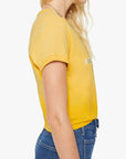 A woman with wavy blonde hair is shown from the side, wearing The Itty Bitty Ringer crop tee by Mother in yellow and blue jeans against a plain white background.