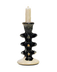 The Creative Co-op Terra-Cotta Taper Holder features a black and cream abstract wavy design, glossy finish, and holds a white candle. This sculptural piece adds modern flair to any room.