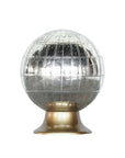 The Wunderkammer Orb by Blue Ocean Traders is a decorative antique-silver glass globe with etched grid lines and vintage accents, set on a metallic gold base. Its reflective surface stands out against a plain white background.