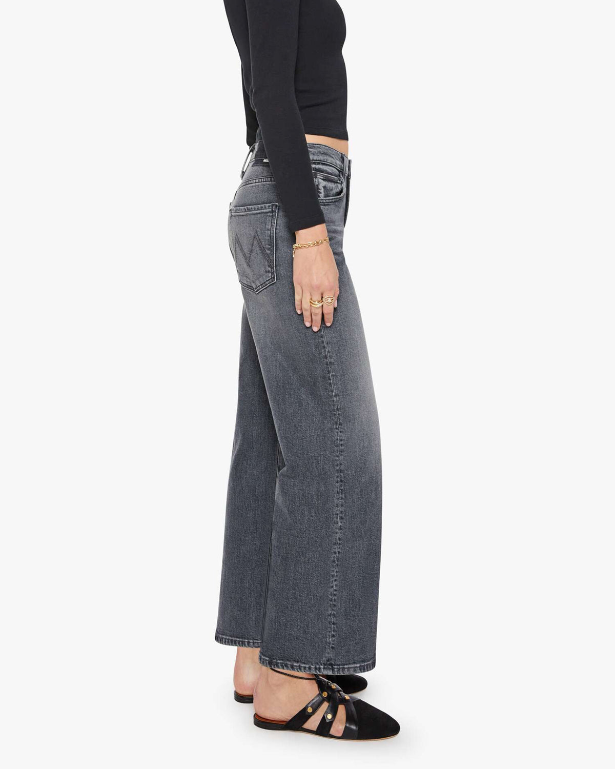 The Dodger Flood jeans by Mother in blue denim, styled with a black top and gold jewelry, side view.