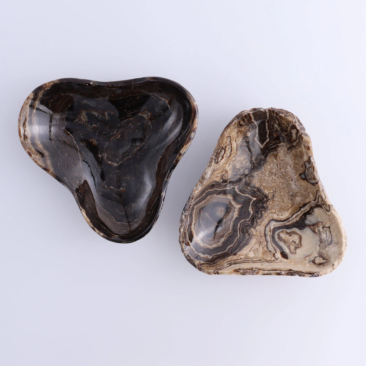 Heart stones beside a Mexican onyx chocolate triangular bowl with swirling patterns from Bungalow Furniture & Accessories.
