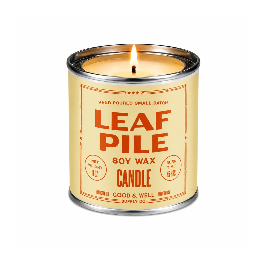 Lit Leaf Pile Soy Candle in a metal tin by Faire, with orange label text on a cream background.